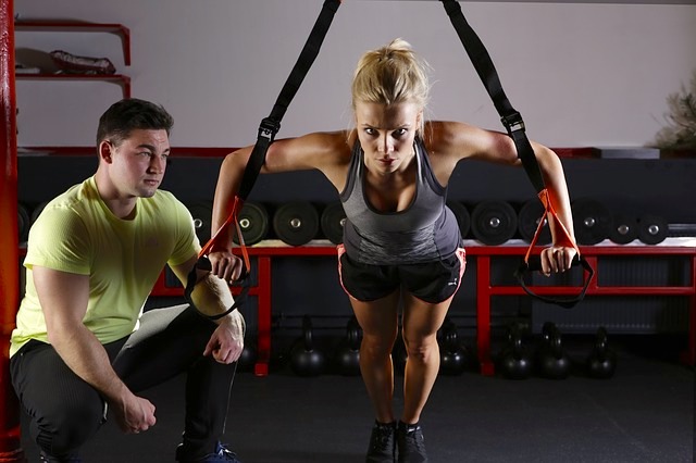 Woman with Trainer doing TRX Exercises.