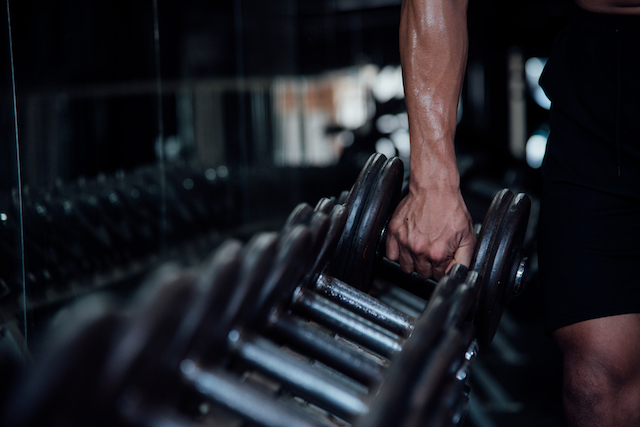 man putting away weights in a gym.