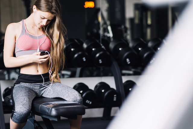 Girl texting on phone while in gym.