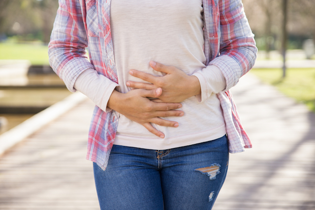 woman holding stomach suffering from bloating.