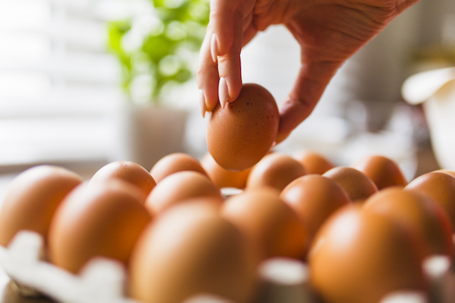 woman's hand grabbing an egg from a carton.