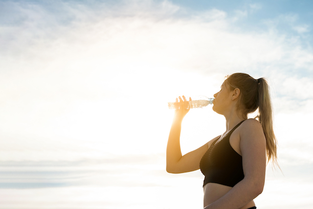 woman drinking from a bottle, looking tired.