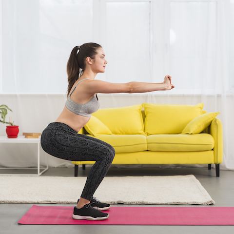 Woman doing a squat in her home.