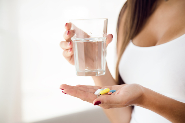 woman taking pills with water.