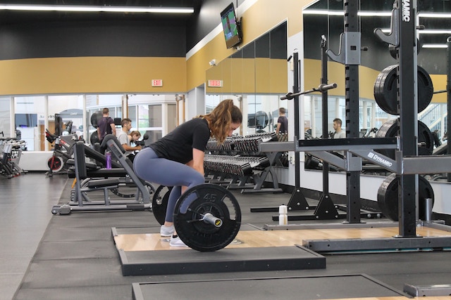 Woman in gym doing deadlift strength exercise.