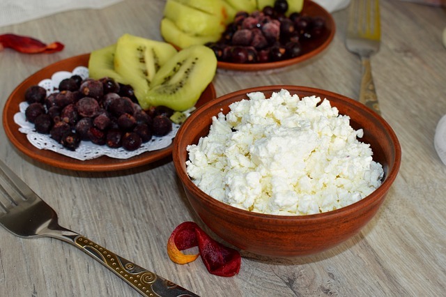 Bowl of cottage cheese with fruit on the side.