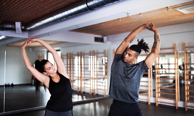 Two people stretching in gym before a workout.