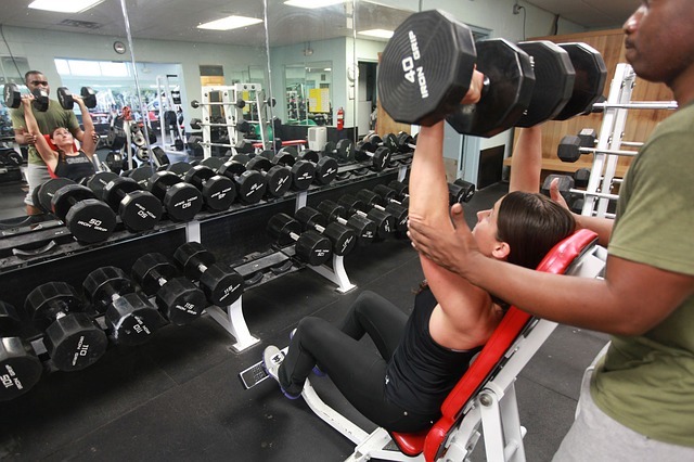 woman doing intense weight lifting with assistance. 