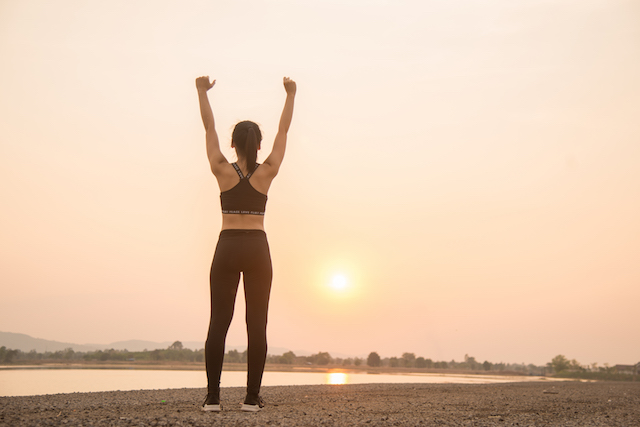 woman runner warming up in front of a sun.