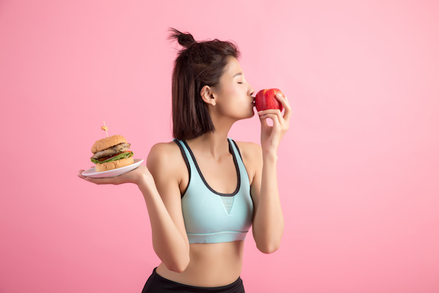 woman choosing a healthy apple over a hamburger.