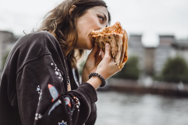 woman eating two slices of pizza at once. 