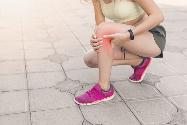 woman kneeling holding her leg pain radiating, due to runner's knee.