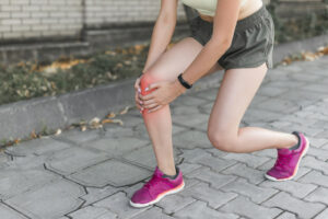 a runner holding her knee in radiating pain.