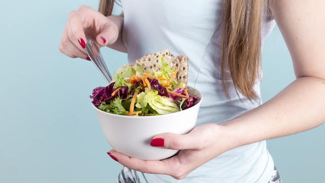 woman eating from a bowl of salad. 