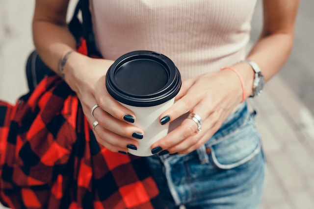 woman holding coffee cup on the go.