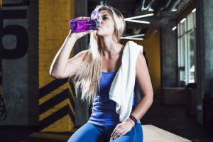 woman at a gym drinking from a bottle.