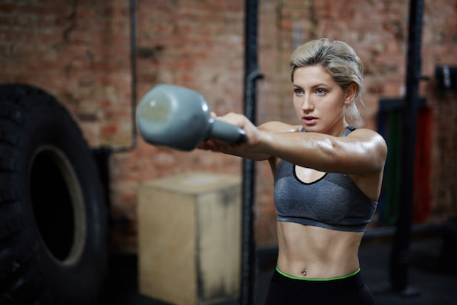 woman lifting kettlebell at nighttime. 