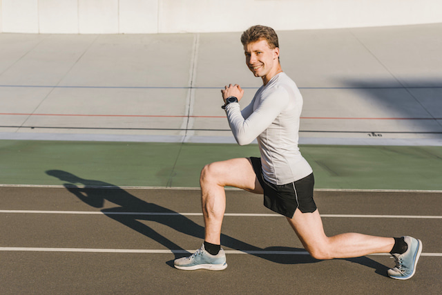 man smiling doing a body weight lunge.