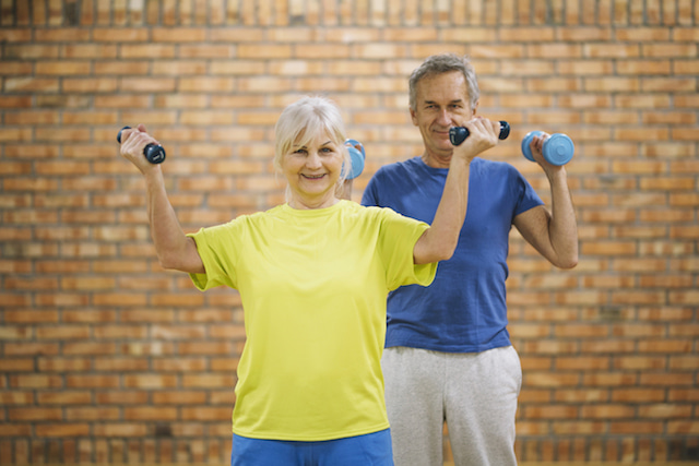 an elderly couple lifting light weights for a low-intensity workout.