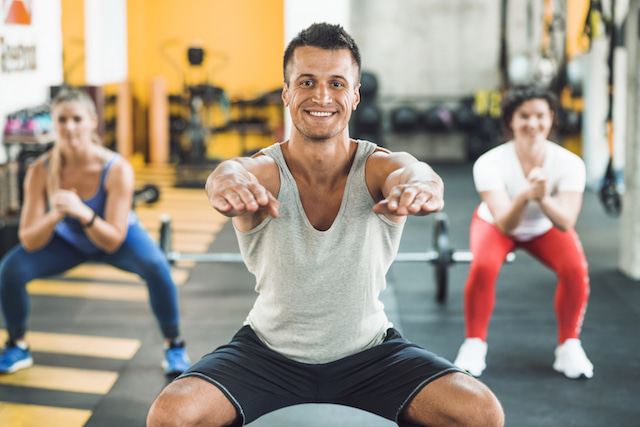 a man and two women doing bodyweight squats.