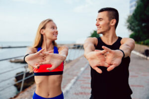 woman and man smiling and stretching preparing for a low-intensity workout