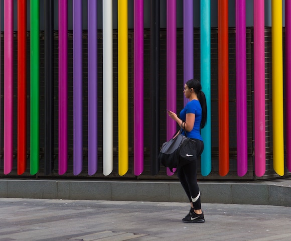 woman walking with her gym bag during her lunch break in a colorful city.